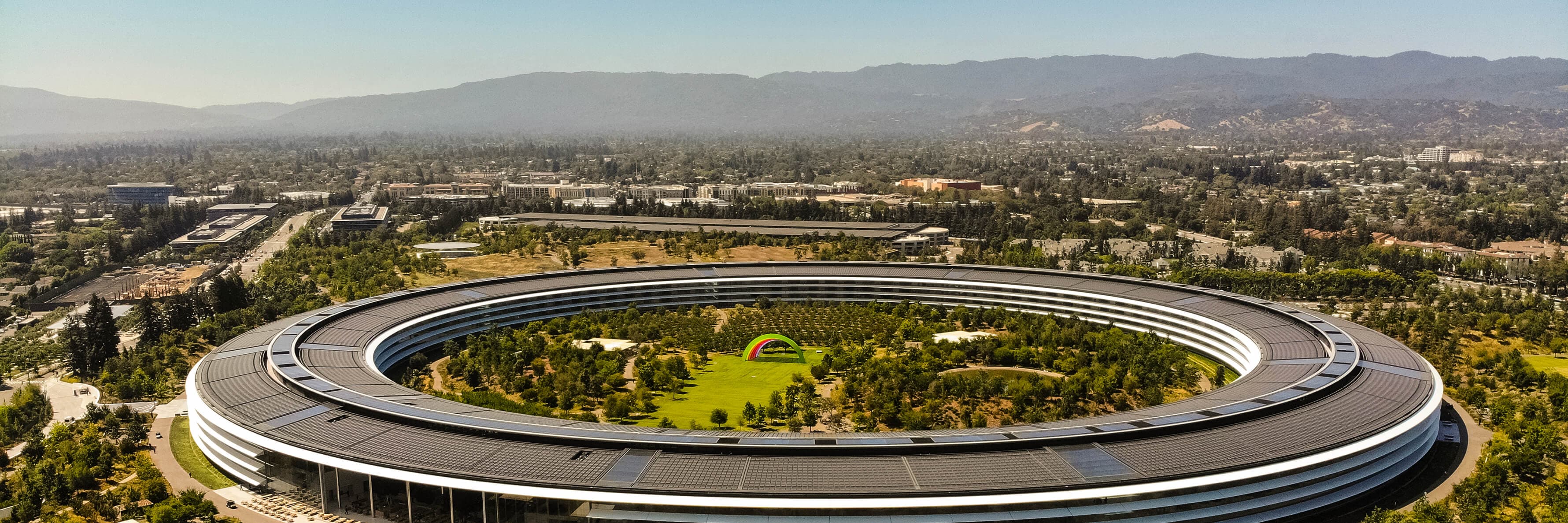 Cars driving past Apple Park, an iconic building located in Sunnyvale California.